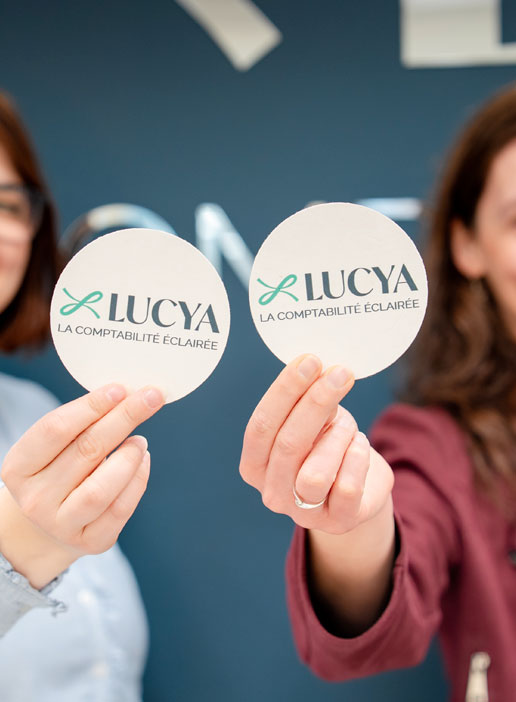 Deux collaboratrices présentant des cartes avec le logo LUCYA – la comptabilité éclairée.